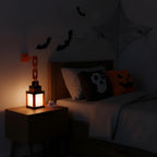 Halloween-themed bedroom with lit lamp, ghost pillow, and spider web.