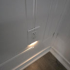 Wall outlet with embedded lighting on a white paneled wall.